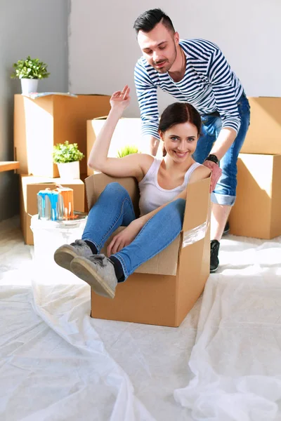 Feliz jovem casal desembalagem ou embalagem caixas e se mudar para uma nova casa — Fotografia de Stock