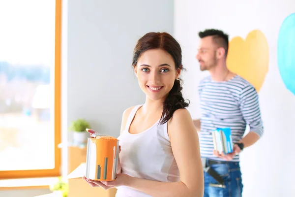 Retrato feliz sonriente joven pareja pintura interior de la pared de la nueva casa —  Fotos de Stock