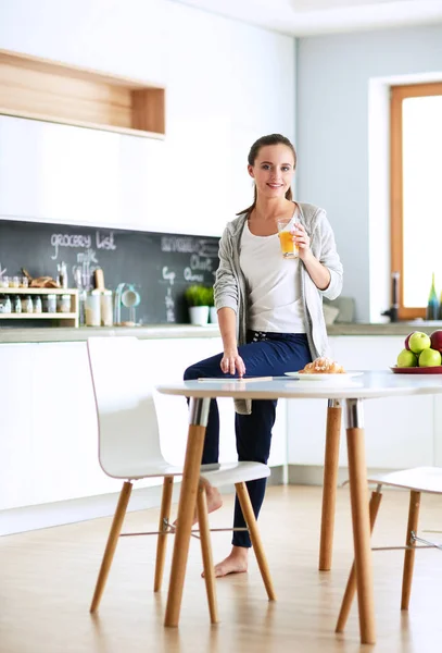 Ung kvinna med apelsinjuice och tablett i köket — Stockfoto