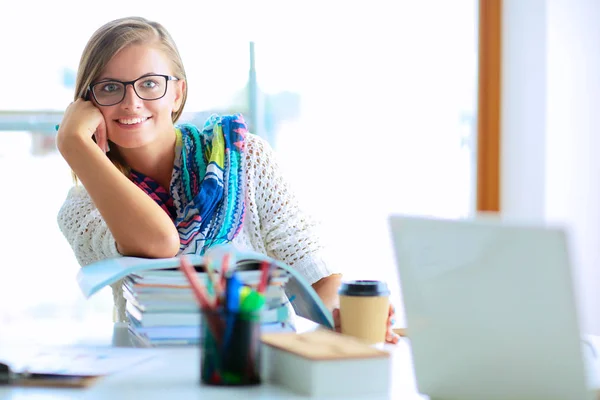 Jeune femme assise à un bureau parmi les livres — Photo