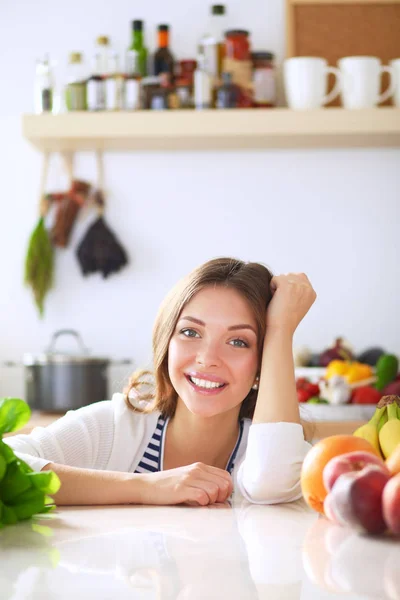 Jonge vrouw in de buurt van bureau in de keuken — Stockfoto