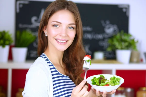 Mujer joven comiendo ensalada y sosteniendo una mezcla — Foto de Stock