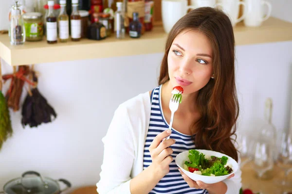Ung kvinna äter sallad och håller en blandad — Stockfoto