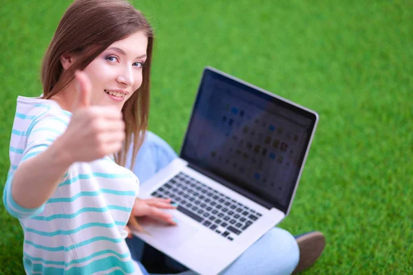 Jeune femme avec ordinateur portable assis sur l'herbe verte — Photo