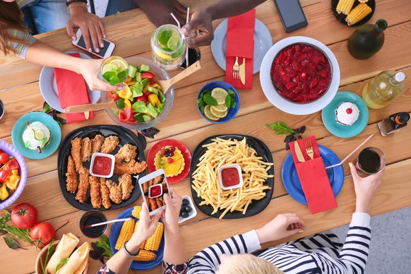 Top view grupo de pessoas jantando juntas enquanto sentadas à mesa de madeira — Fotografia de Stock