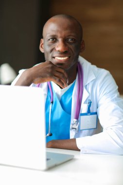 Masada dizüstü bilgisayarda çalışan genç bir Afrikalı doktor.