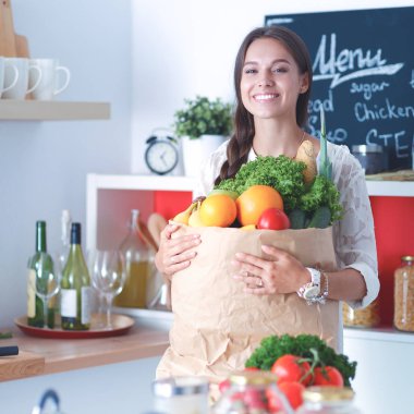 Elinde sebzeli alışveriş torbası tutan genç bir kadın.