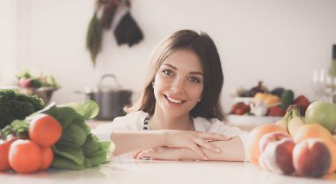 Mutfakta masanın yanında duran genç bir kadın.