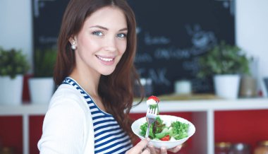 Salata yemek ve karışık salata tutan genç kadın