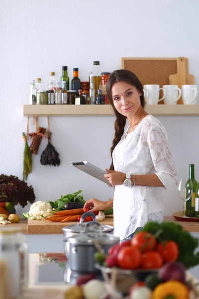 Young woman using a tablet computer to cook in her kitchen — Stock Photo, Image