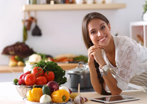 Jovem usando um computador tablet para cozinhar em sua cozinha — Fotografia de Stock