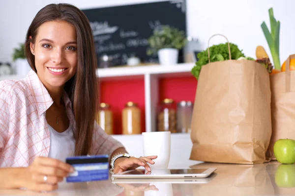 Lächelnde Frau beim Online-Shopping mit Tablet und Kreditkarte in der Küche — Stockfoto