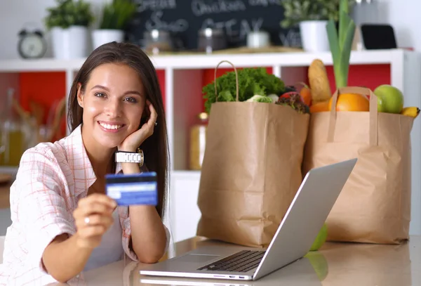 Lachende vrouw online winkelen met behulp van Tablet PC- en creditcard in keuken — Stockfoto