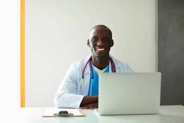 机の上でノートパソコンで働く若いアフリカ人医師 — ストック写真