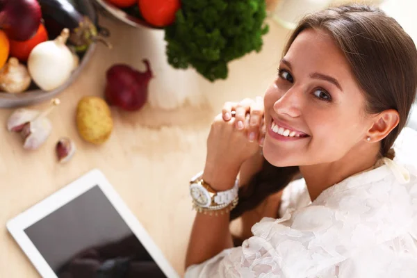 Jovem usando um computador tablet para cozinhar em sua cozinha — Fotografia de Stock