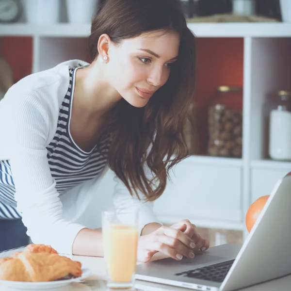 Attraktiv ung kvinna med laptop och sitter i köket — Stockfoto