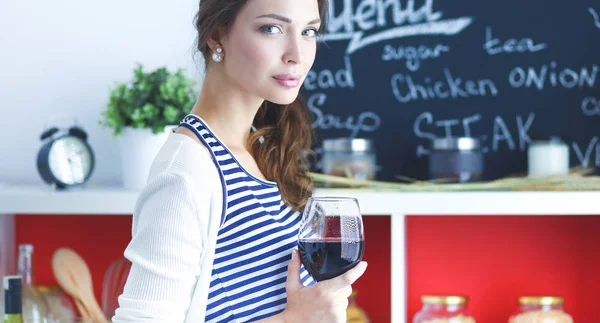 Mujer bonita bebiendo un poco de vino en casa en la cocina —  Fotos de Stock