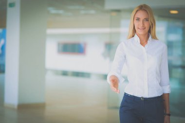 Genç iş kadını ofiste el sıkışmaya hazır.