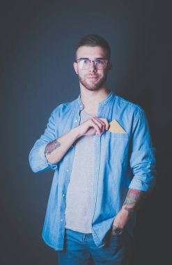 Elinde kredi kartı olan bir adam gri arka planda duruyor.