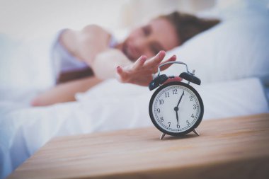 Evdeki yatak odasında uyuyan genç kadın ve çalar saat.