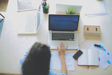 Ofis masasında dizüstü bilgisayarıyla oturan genç bir kadın.