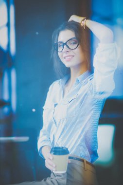 Ofis masasında dizüstü bilgisayarlı genç bir kadın oturuyor, pencereden bakıyor.