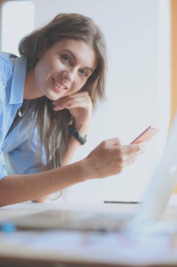 Masasında enstrümanlar, planlar ve dizüstü bilgisayarlarla oturan genç bir kadın.