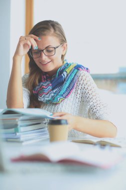 Kitapların arasında masa başında oturan genç bir kadın.