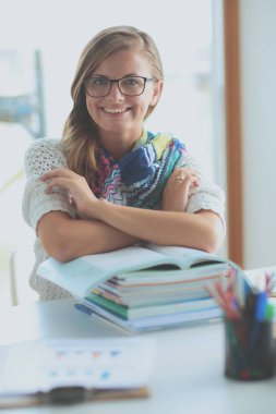 Kitapların arasında masa başında oturan genç bir kadın.