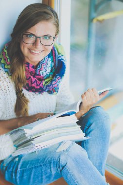 Kitapların arasında masa başında oturan genç bir kadın.