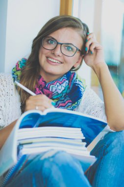 Kitapların arasında masa başında oturan genç bir kadın.