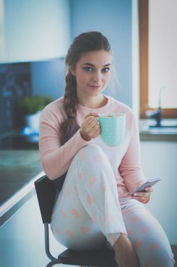 modern mutfakta otururken cep telefonu kullanan kadın