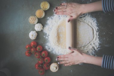 Güzel bir kadın mutfakta pasta pişiriyor. Masanın yanında duruyor.