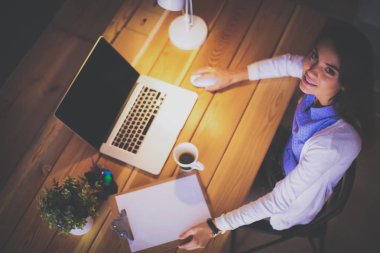 Masada oturan genç bir kadın.