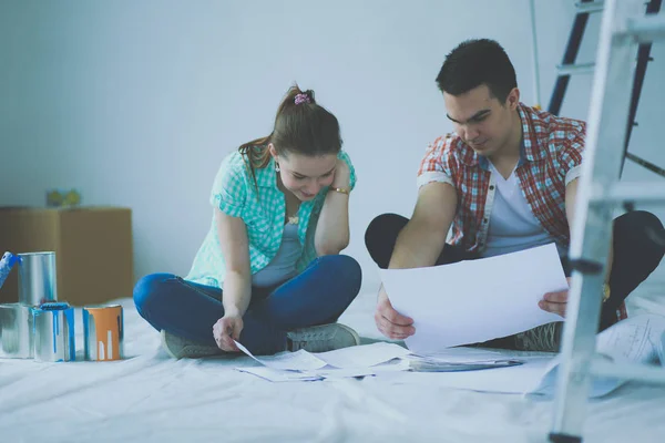 Pareja joven sentada en el suelo y calculando sobre sus ahorros —  Fotos de Stock