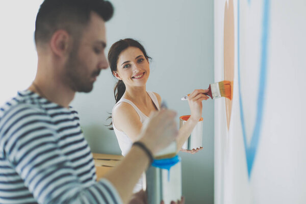 Portrait happy smiling young couple painting interior wall of new house