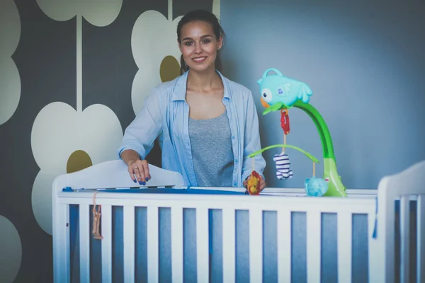 Mooie jongedame permanent in de buurt van kinderen kinderbed — Stockfoto