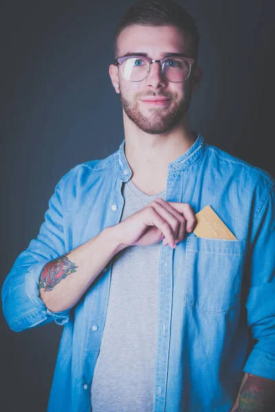 Hombre sosteniendo una tarjeta de crédito de pie sobre fondo gris — Foto de Stock