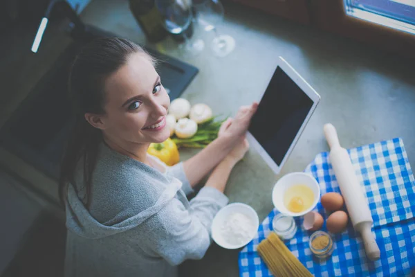 Kvinna bakning hemma efter recept på en tablett — Stockfoto