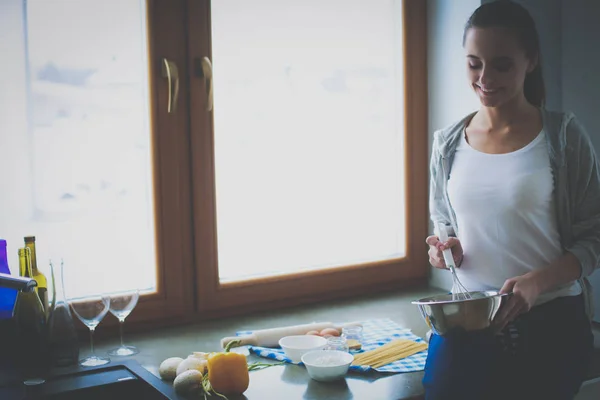 Mujer joven cocinando panqueques en la cocina de pie cerca de la estufa — Foto de Stock