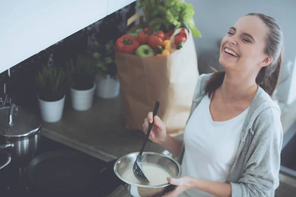Молодая женщина готовит блины на кухне, стоящей рядом с плитой — стоковое фото