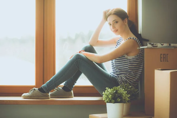 Chica sentada en el alféizar de la ventana en el nuevo hogar con taza — Foto de Stock