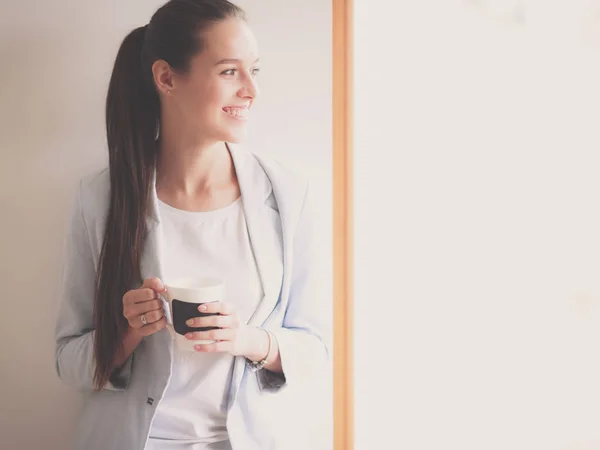 Attractive woman sitting at desk in office having takeaway coffee — Stock Photo, Image