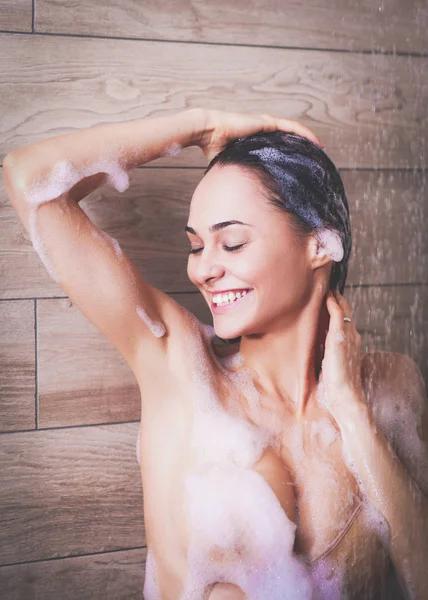 Jeune femme belle sous la douche dans la salle de bain — Photo