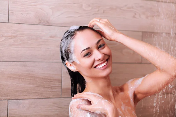 Jeune femme belle sous la douche dans la salle de bain — Photo