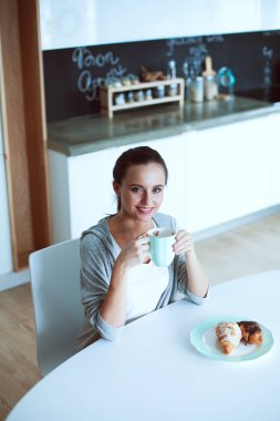 Mutfak masasında tatlı kruvasan ile çay içme kadın