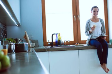 Mutfakta dijital tablet kullanan güzel genç bir kadın.