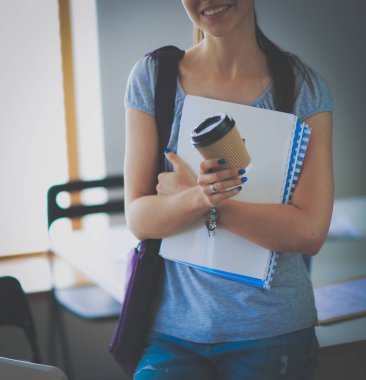 Klasörler ve kahve ile gülümseyen öğrenci