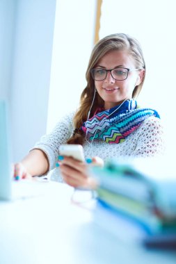 Kitapların arasında masa başında oturan genç bir kadın.