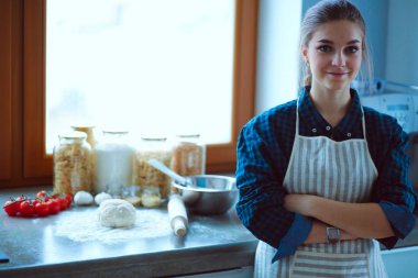 Mutfakta sobanın yanında duran genç bir kadın.